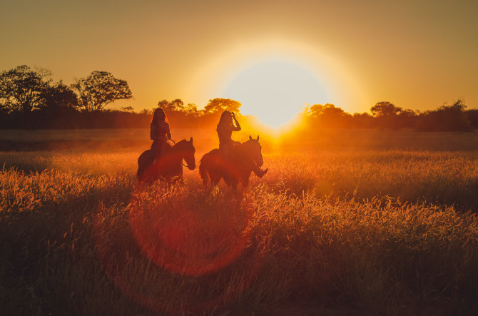 Fotografia di due donne a cavallo durante il tramonto