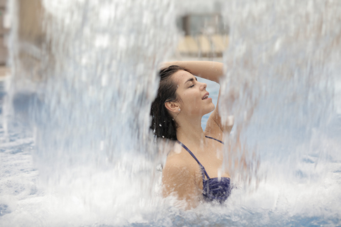 Donna in piscina fotografata in mezzo a due getti d'acqua