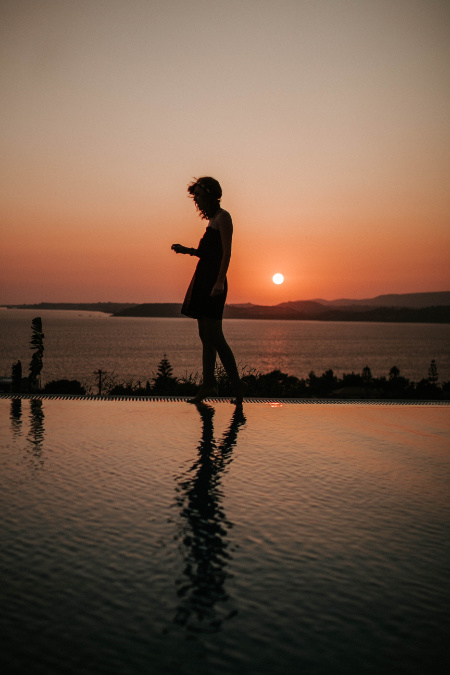 Silhouette di una donna al tramonto a bordo piscina