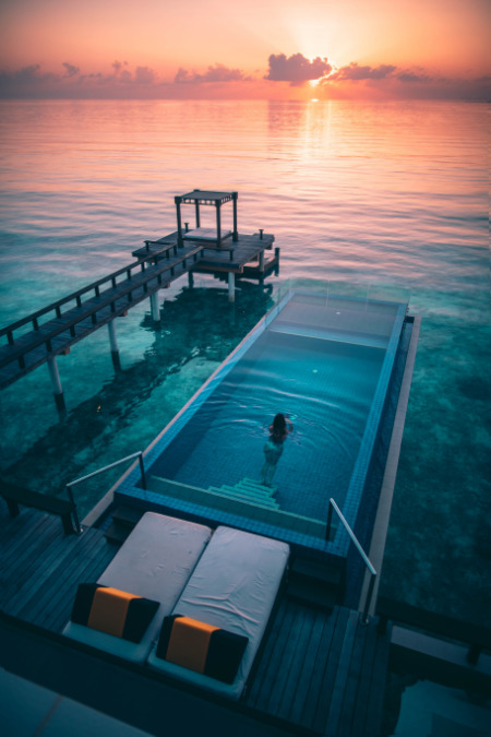 Donna che nuota in piscina al tramonto