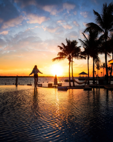 Silhouette di una donna al tramonto a bordo piscina