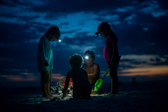 Fotografia di bambini che giocano in spiaggia di notte