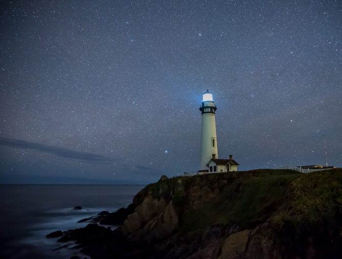 Fotografia di un faro sopra una scogliera