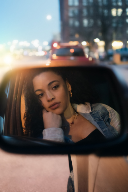 Specchietto laterale di una macchina dove si riflette il volto di una ragazza