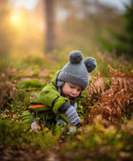 Bambino in un bosco ricco di foglie autunnali
