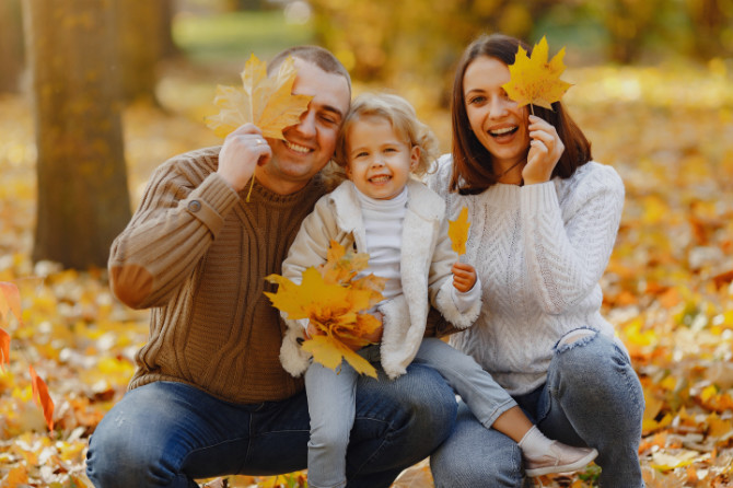 Ritratto di famiglia in un parco pieno di foglie autunnali