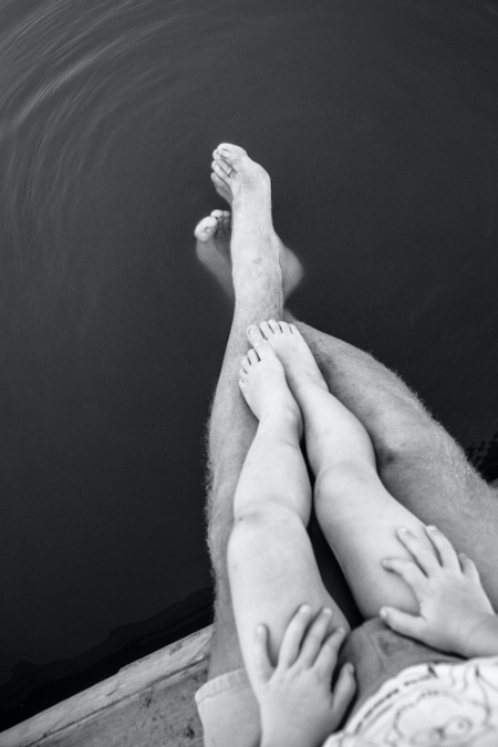 Foto dettaglio in bianco e nero delle gambe di un papà e del figlio