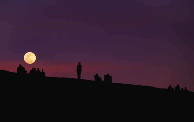 Fotografia della luna piena con silhouette di soggetti in primo piano