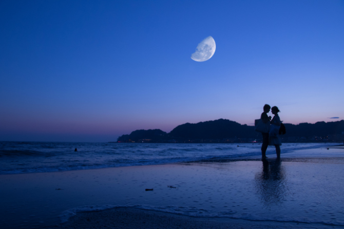 Fotografia della luna con silhouette di soggetti in primo piano