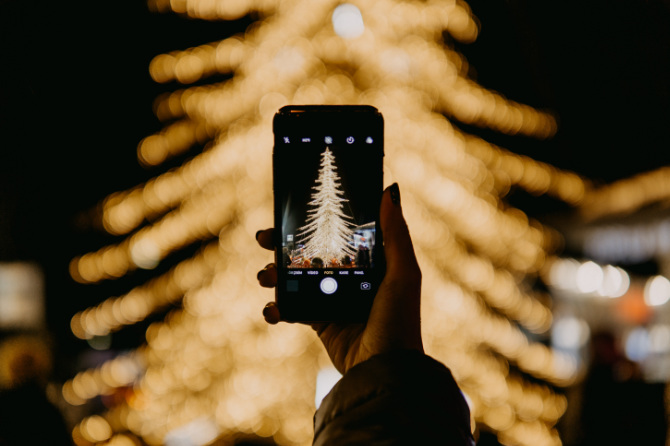 Ragazza fa una foto con lo smartphone ad un albero di Natale